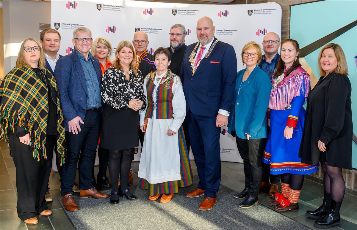 Flere personer står på rekke og smiler til kamera - Klikk for stort bilde